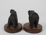 pair of black bear figurines on wooden bases on a white background