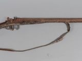 un vieux fusil avec une poignée en bois sur une surface blanche