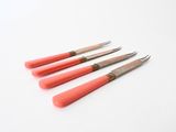 four red handled knives sitting next to each other on a white surface