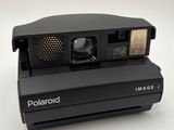 an old polaroid camera sitting on top of a white surface