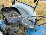un vieux tracteur bleu garé dans un champ d'herbes hautes