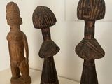 three wooden figurines sitting on a shelf next to a knife