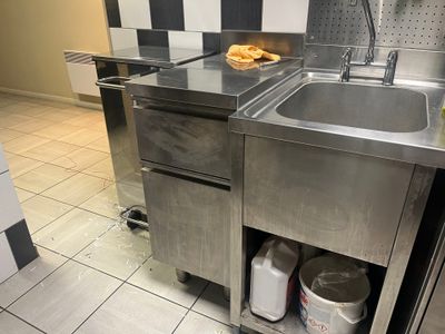 un évier en acier inoxydable dans une cuisine aux murs à carreaux noirs et blancs