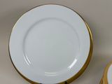 a white plate with a gold rim next to a white plate with a gold rim