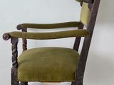 an old wooden chair with a green upholstered seat