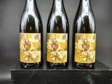 trois bouteilles de vin posées sur une caisse en bois