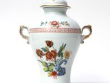 a white vase with flowers on it on a white surface