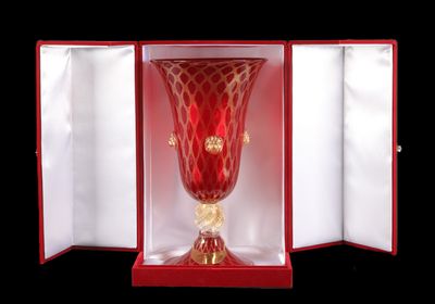 un vase en verre rouge dans une boîte rouge sur fond noir