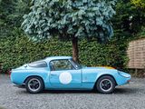 a blue car parked in a parking lot next to a tree