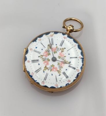 a small gold pocket watch with a floral design on it