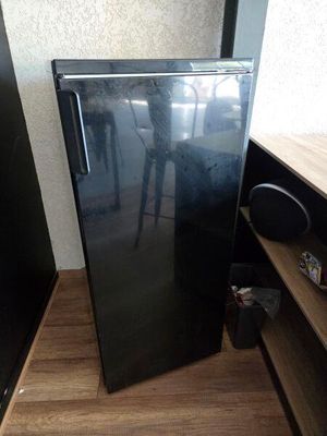 un petit réfrigérateur noir dans un coin de la pièce