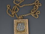 a gold and diamond necklace with a monogram on it