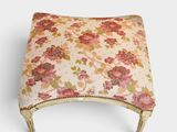 un repose-pieds rembourré orné d'un motif floral et d'une bordure dorée