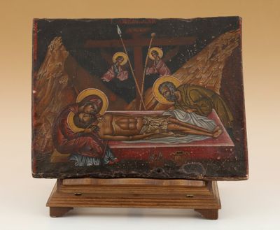 une vieille peinture représentant Jésus sur la croix, posée sur un socle en bois