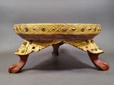 a gold and red bowl on a stand on a gray surface