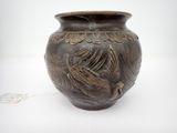 un vase brun posé sur une surface blanche