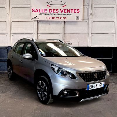 La voiture argentée est garée devant un panneau indiquant « soldes ».
