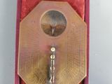 a gold clock in a red box on a white surface