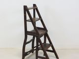 an old wooden step stool sitting in a room next to a white wall