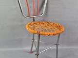 une chaise en métal avec une assise en osier sur fond gris