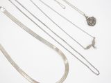 a lot of silver necklaces on a white surface
