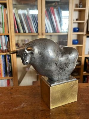 une statue en bronze représentant un taureau, posée sur une table en bois