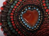 a close up of a beaded bracelet with a heart on it