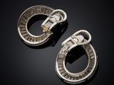 a pair of silver and diamond earrings on a black surface