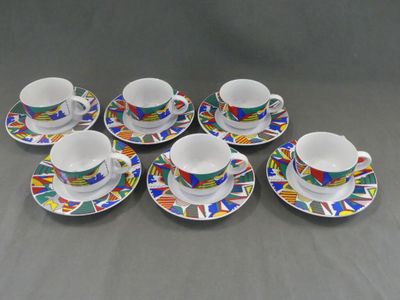 six tasses et soucoupes ornées de motifs colorés, posées sur une table