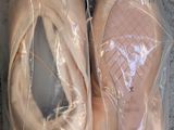 two pairs of ballet shoes wrapped in plastic on the floor