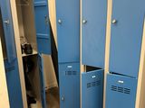 several blue lockers in the corner of a room with shoes on the floor