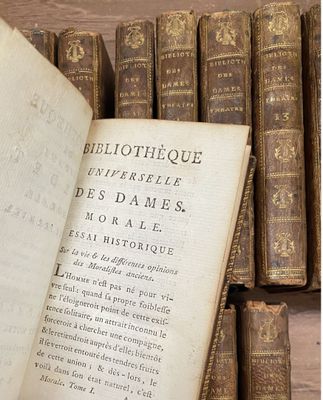 un vieux livre posé sur une table en bois, à côté d'une pile de livres
