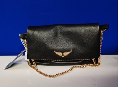 un sac à main noir orné d'une aile dorée sur le devant