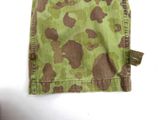 a green and brown camouflage cloth with a tag on it