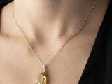 une femme portant un collier en or orné d'un pendentif jaune en forme de larme