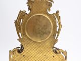 a gold clock that is sitting on a stand