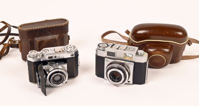 two old cameras sitting next to each other on a white surface