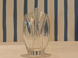 a glass vase sitting on a table with a striped wall behind it