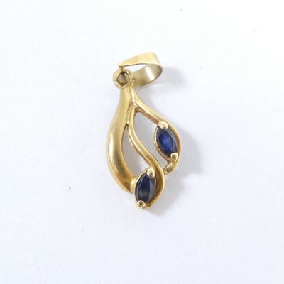 un gros plan d'un pendentif en or orné de pierres bleues sur un fond blanc
