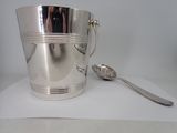 a silver ice bucket with a spoon and spoon on the table