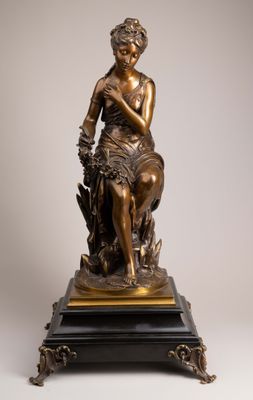 an antique bronze statue of a woman sitting on a tree stump
