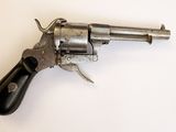 un gros plan d'un revolver posé sur une surface blanche, avec une crosse noire