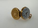 a gold pocket watch sitting on a white surface