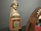 a statue of a woman holding a clock on top of a wooden pole