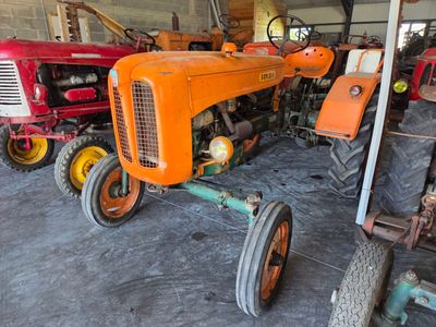 many old tractors that are sitting in a garage