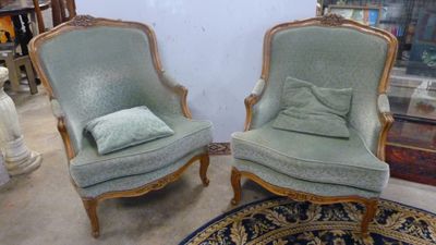 une paire de chaises vertes avec des coussins posés dessus, dans une pièce