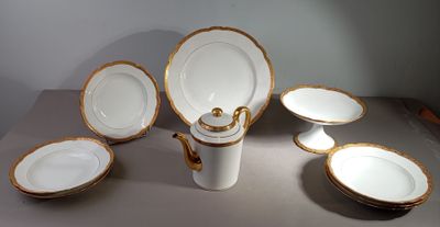 plusieurs assiettes et bols en porcelaine blanche et dorée posés sur une table