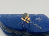 une photo d'une bague en or sertie d'une pierre noire