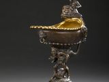 paire de vases en bronze ornés de figures, posés sur un socle, sur fond gris