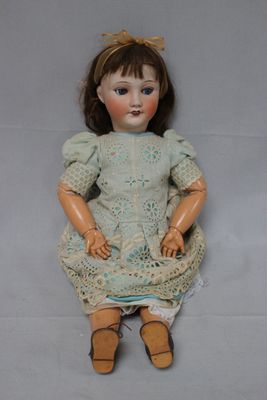 an image of a doll sitting on the ground with a dress on